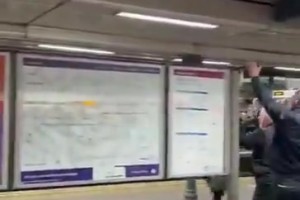 曼城球迷车站站台挥旗‘骑脸’庆祝，阿森纳球迷默默注视着